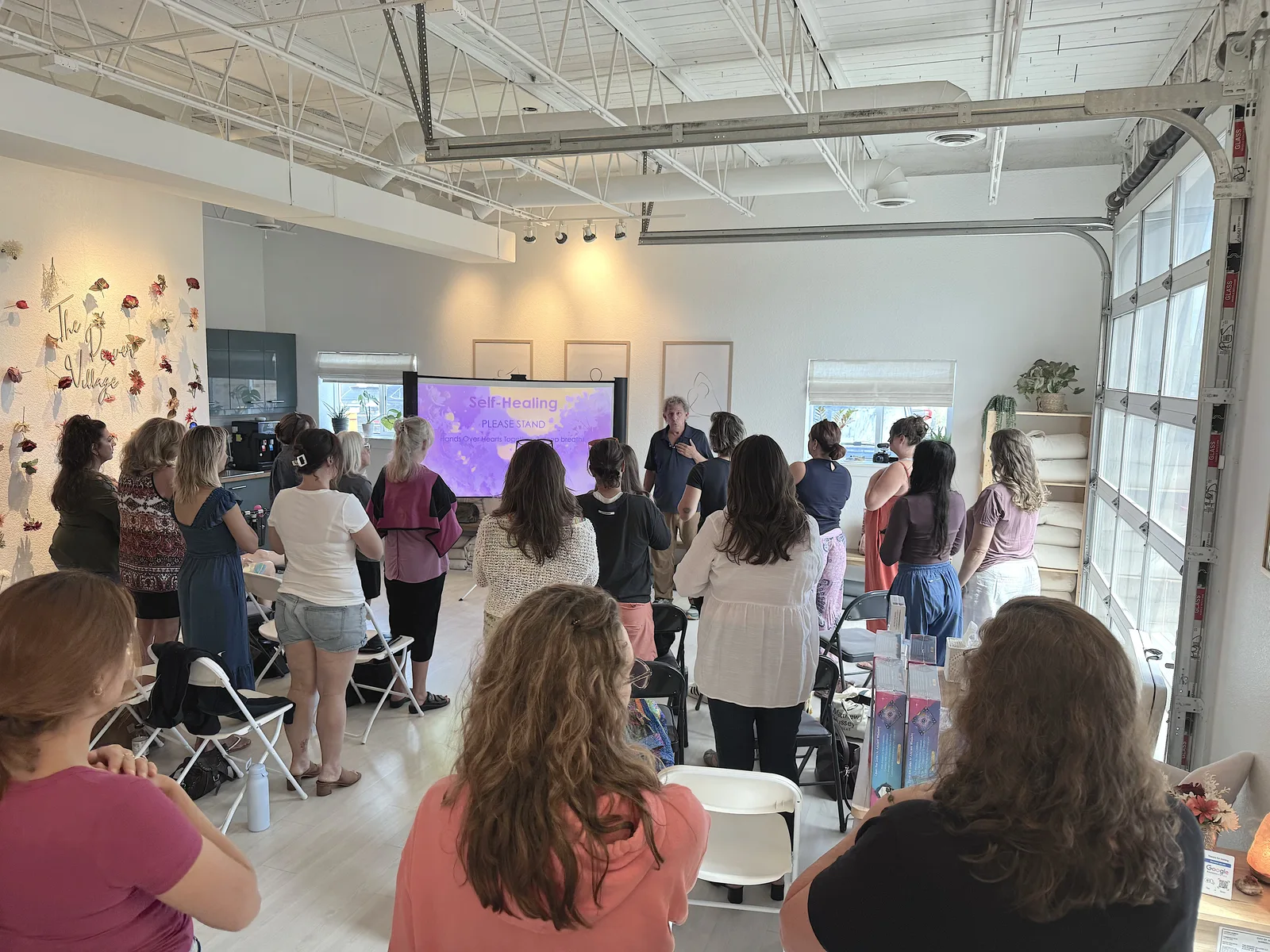 Paul leading a standing self-healing practice with an indoor workshop group